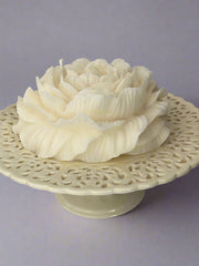 Decorative white ceramic flower on a matching stand with intricate designs against a gray background