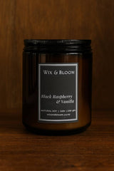 Black candle jar with 'Wix & Bloom' label on a wooden background