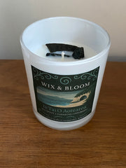 Candle in a white container with a label on a wooden surface