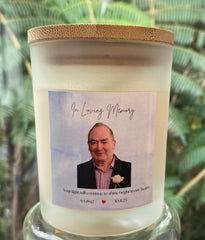 A personalized memorial candle in a frosted glass jar with a bamboo lid, featuring a custom photo label that reads 'In Loving Memory' 